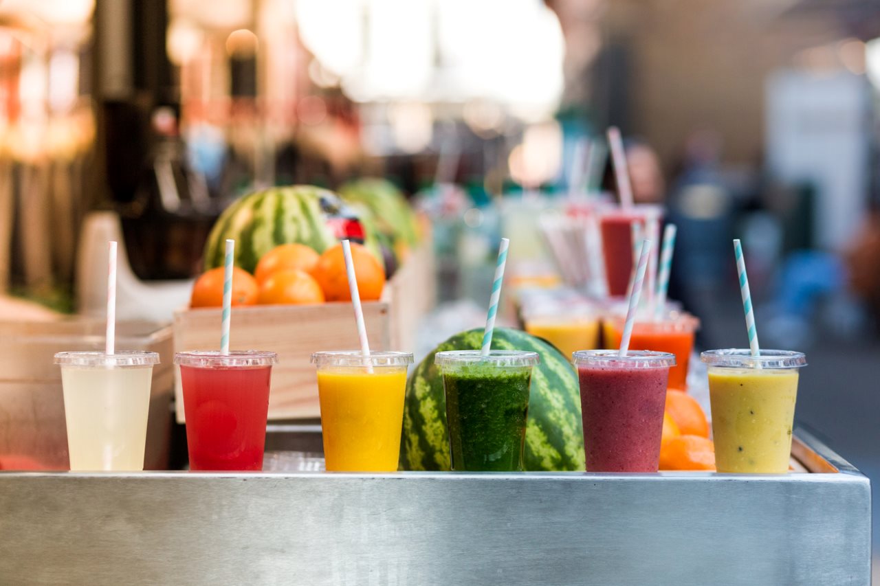 freshly made fruit juices and smoothies on display in a row