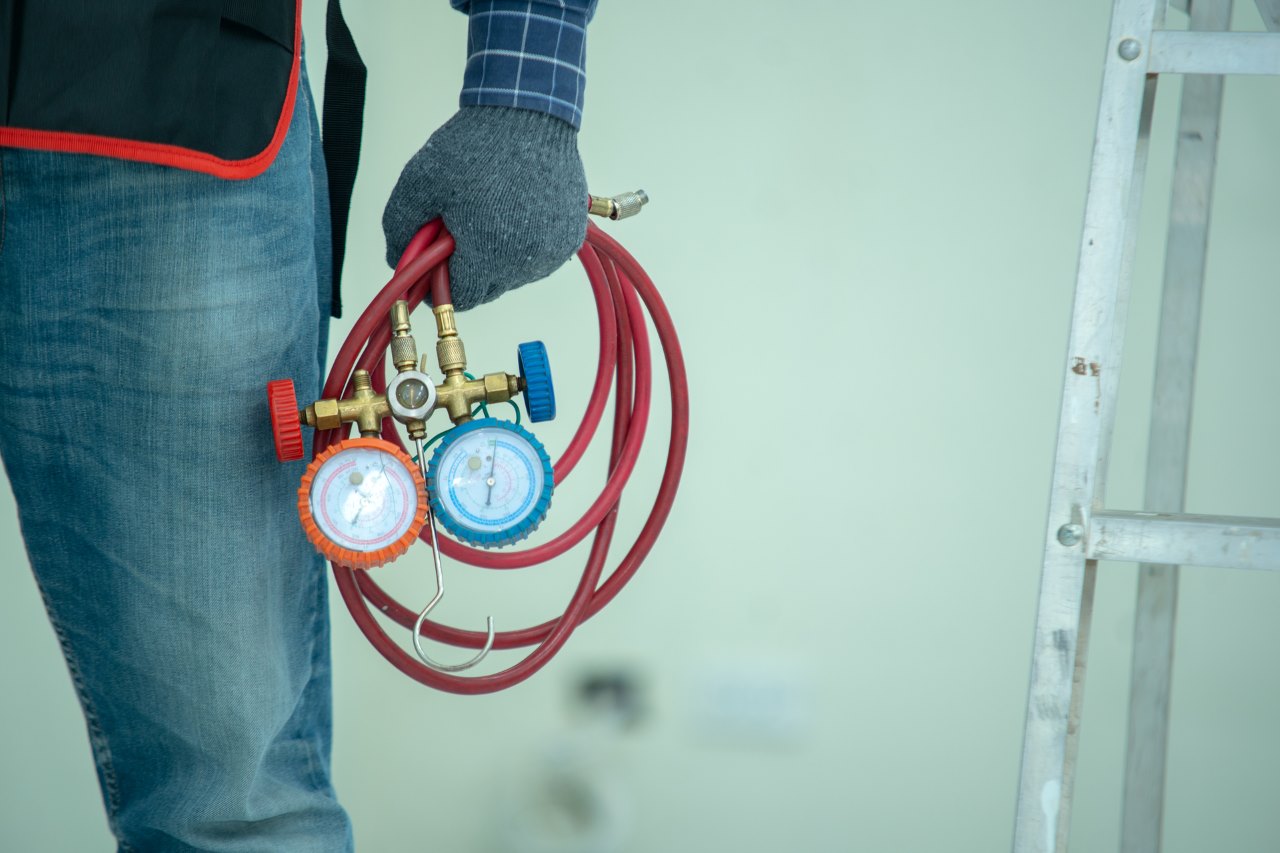 technician holding a manifold gauge used to diagnose and repair refrigerators or cooling systems